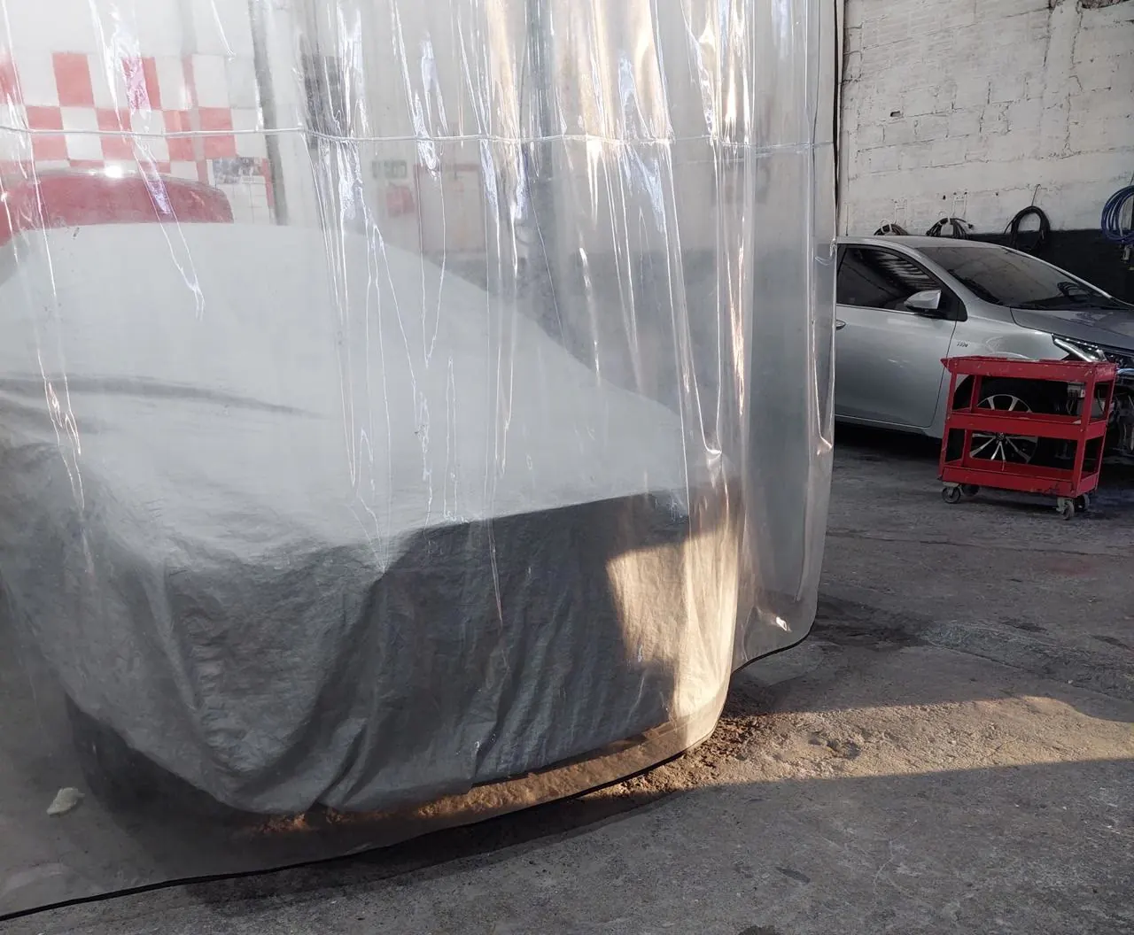 Carro cubierto dentro de la cabina de preparación, listo para pintura automotriz